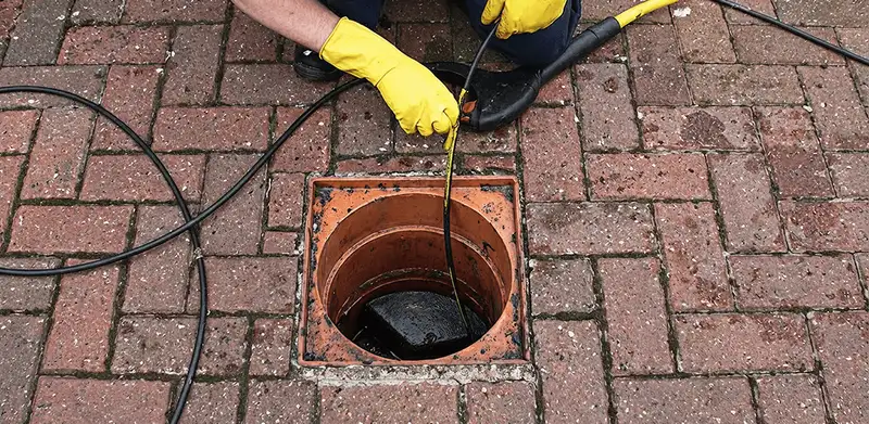 Drain cleaning technician using a drain snake to clear a clogged drain in Chula Vista, CA