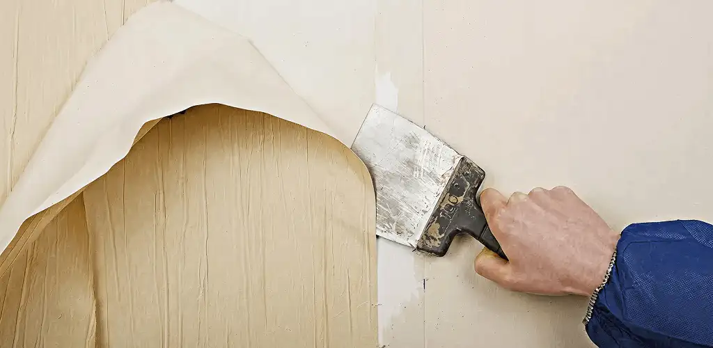 Handyman removing wallpaper with a scraper for wall preparation in Chula Vista, CA