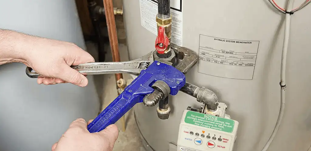 Water heater repair technician tightening the shutoff valve and supply line in Chula Vista, CA
